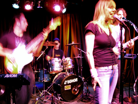 Mobius Donut on stage in Walnut Creek. Kevin on the left blurred, Kerry on drums in the background, Cindy Lou and Andrea on the right